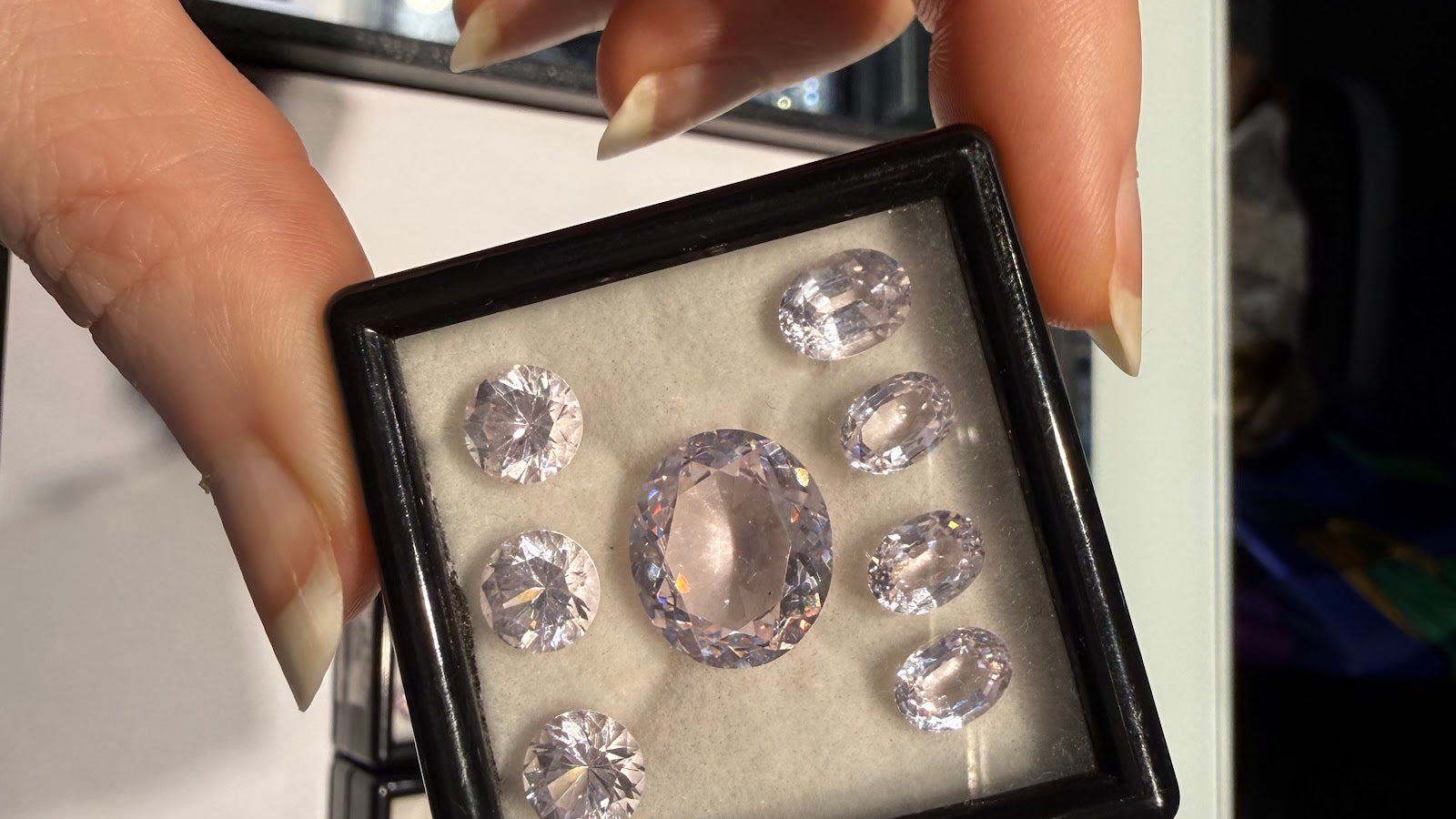 A collector examines a gem box of pastel pink oval and round-cut gemstones at Sapphire Row, the kind of matched parcel prized by colored gemstone collectors