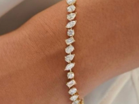 Line bracelet of mixed fancy-cut white gemstones in yellow gold worn on the wrist, photographed at Sapphire Row