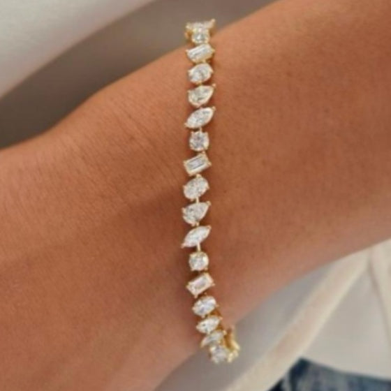 Line bracelet of mixed fancy-cut white gemstones in yellow gold worn on the wrist, photographed at Sapphire Row