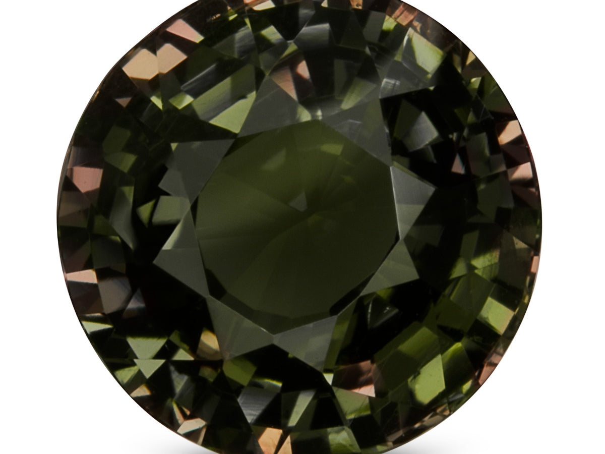 Round brilliant-cut alexandrite from Sri Lanka on a white background, showing a dark grayish olive green body with flashes of brownish pink and orange in the facets