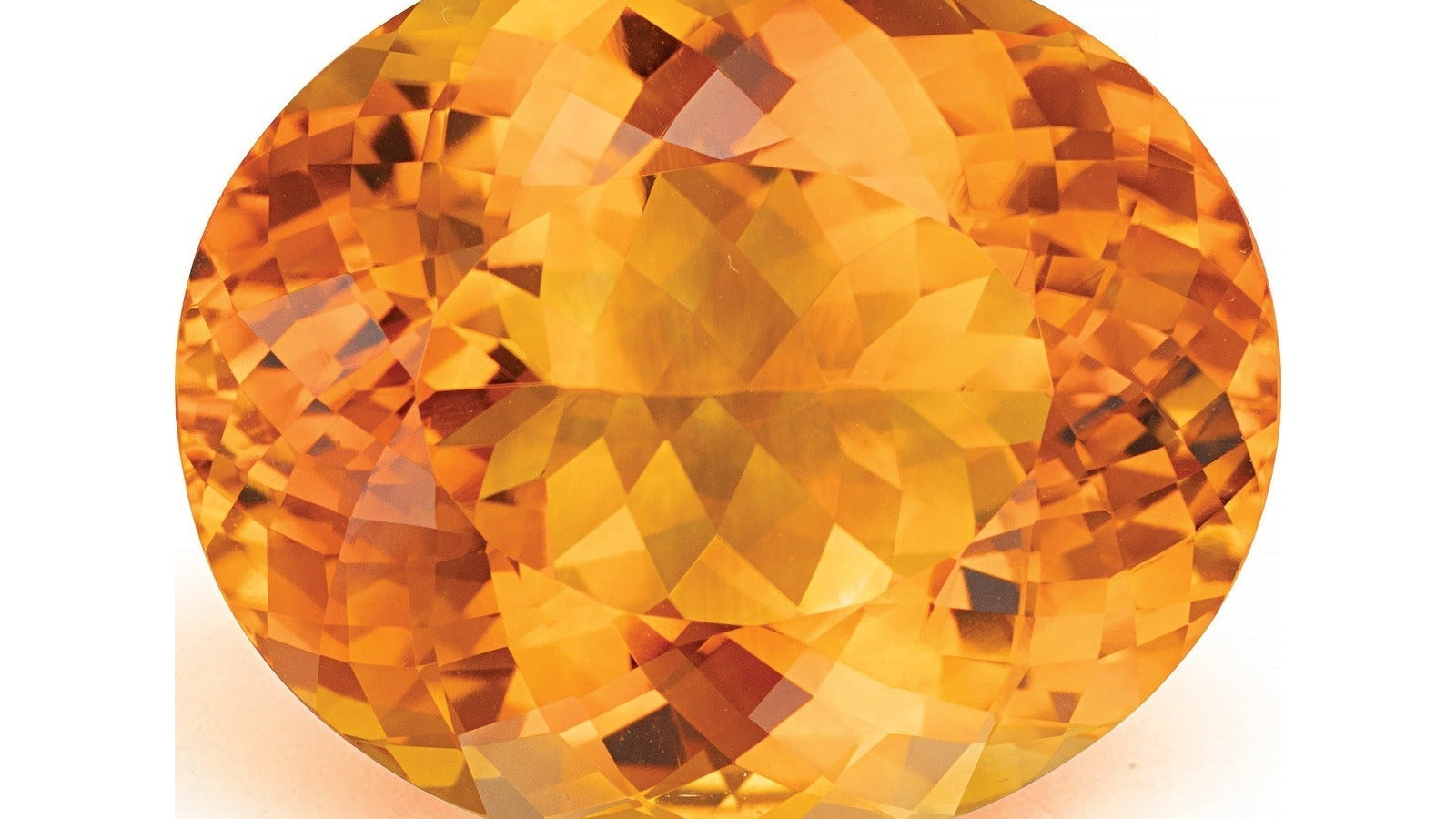 Large oval checkerboard-cut natural citrine from Brazil in a vivid medium orange with a golden yellow core and deeper reddish flashes through the pavilion, photographed face-up on a white background at Sapphire Row