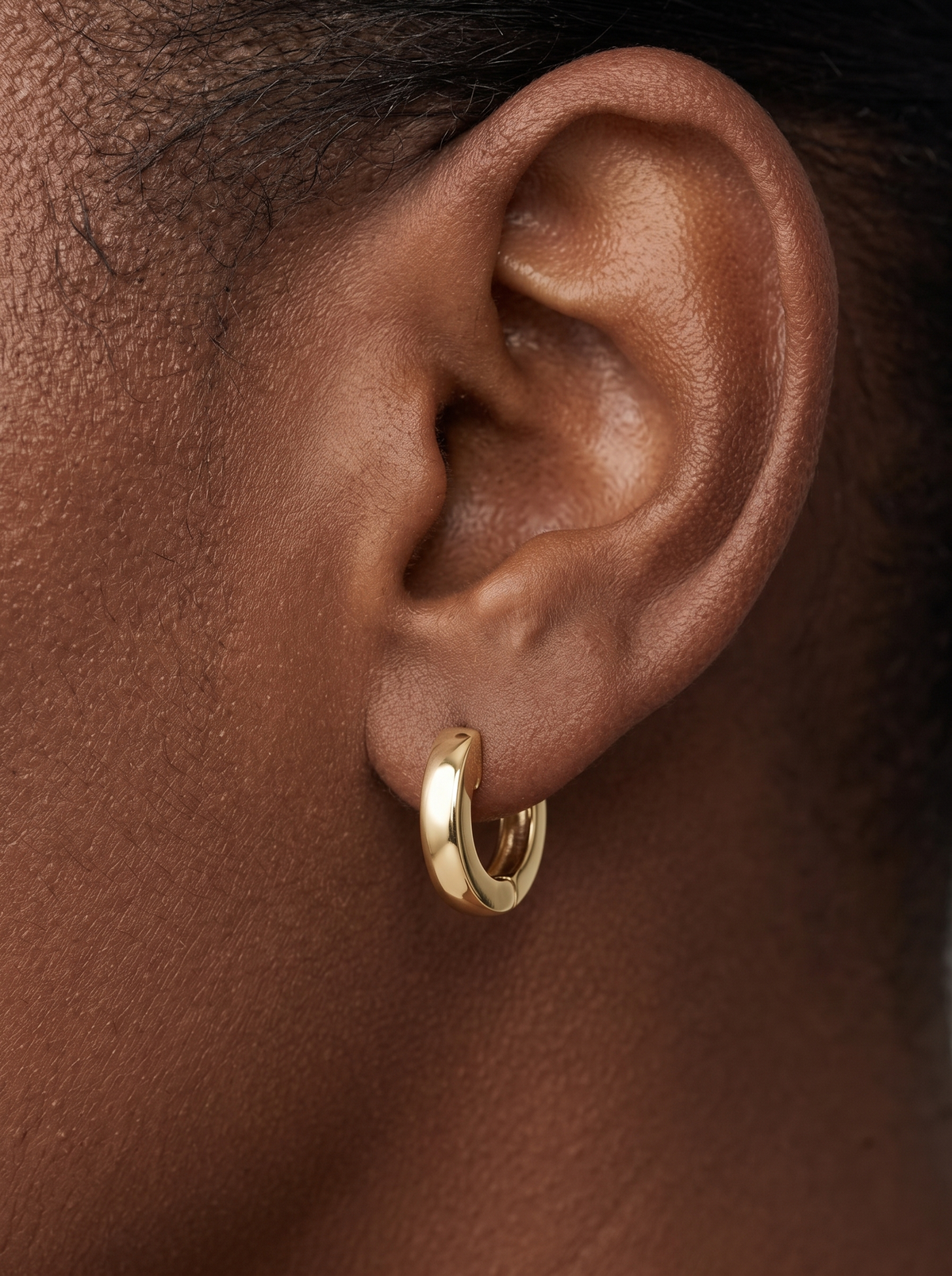Gold Thick Huggie Earrings in 10K Yellow Gold, shown close on the ear