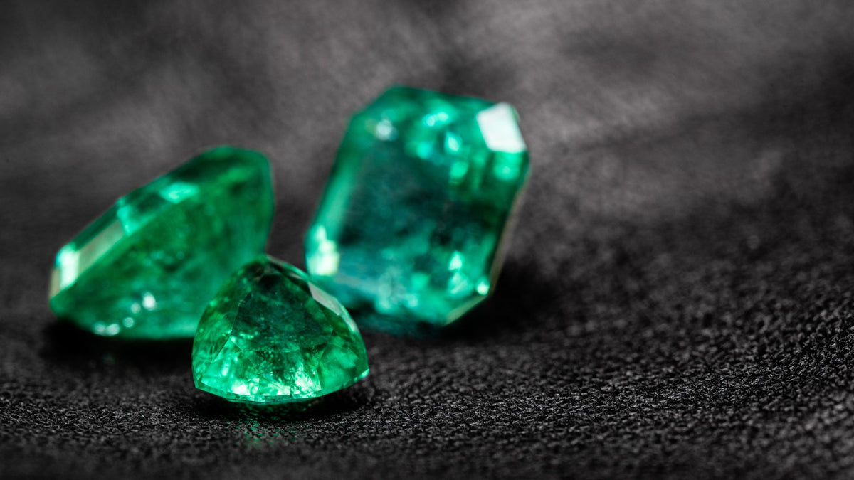 Loose green emerald gemstones on a dark background