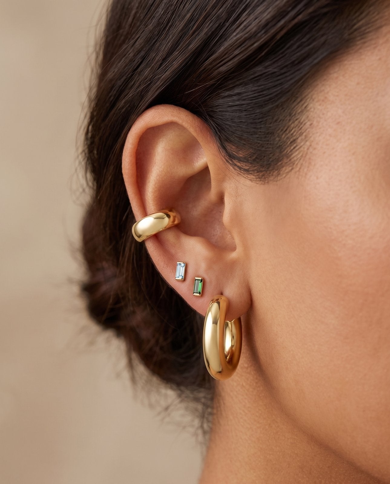 Lab-Grown Aqua Sapphire Channel-Set Baguette Stud Earrings in 14K Yellow Gold, worn on the upper earlobe in a gold ear stack