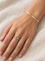 Natural Sky Blue Topaz Chain Ring in 14K Yellow Gold, worn on the hand resting on ivory linen with a herringbone bracelet