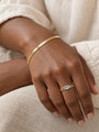 Natural Sky Blue Topaz Chain Ring in 14K Yellow Gold, shown close on the gently curled hand with a herringbone bracelet