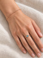 Natural Sky Blue Topaz Chain Ring in 14K Rose Gold, worn on the hand resting on ivory linen with a petite paperclip bracelet