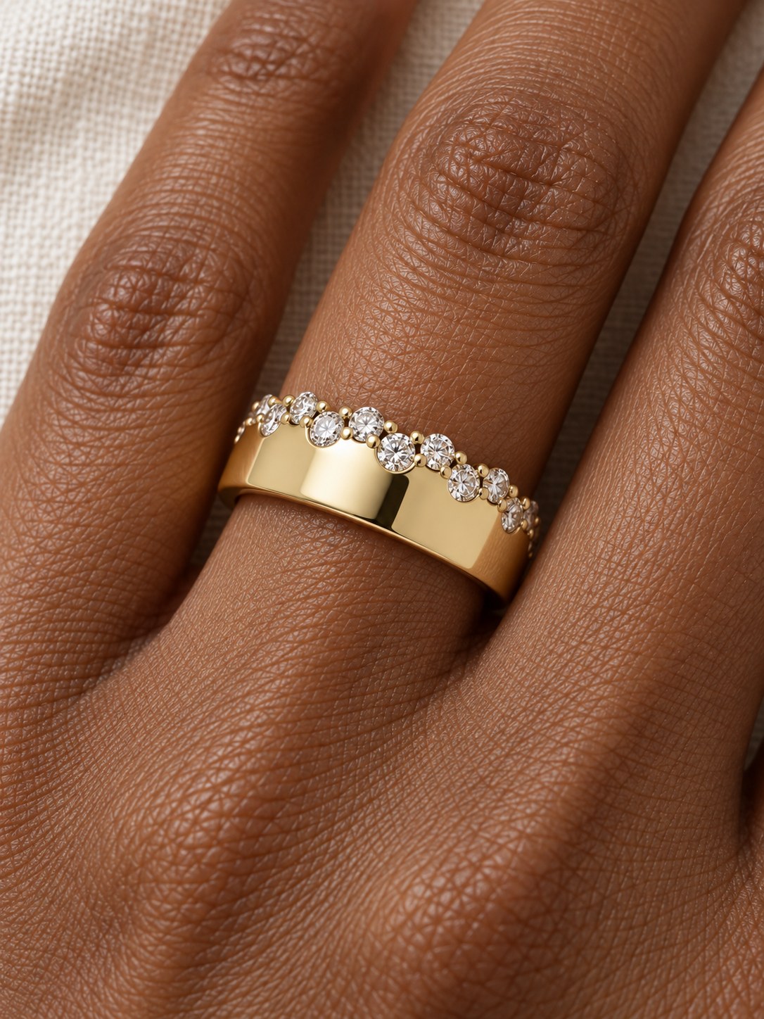 Natural Diamond Cigar Band in 14K Yellow Gold, shown close on the finger, polished gold face with a staggered diamond edge