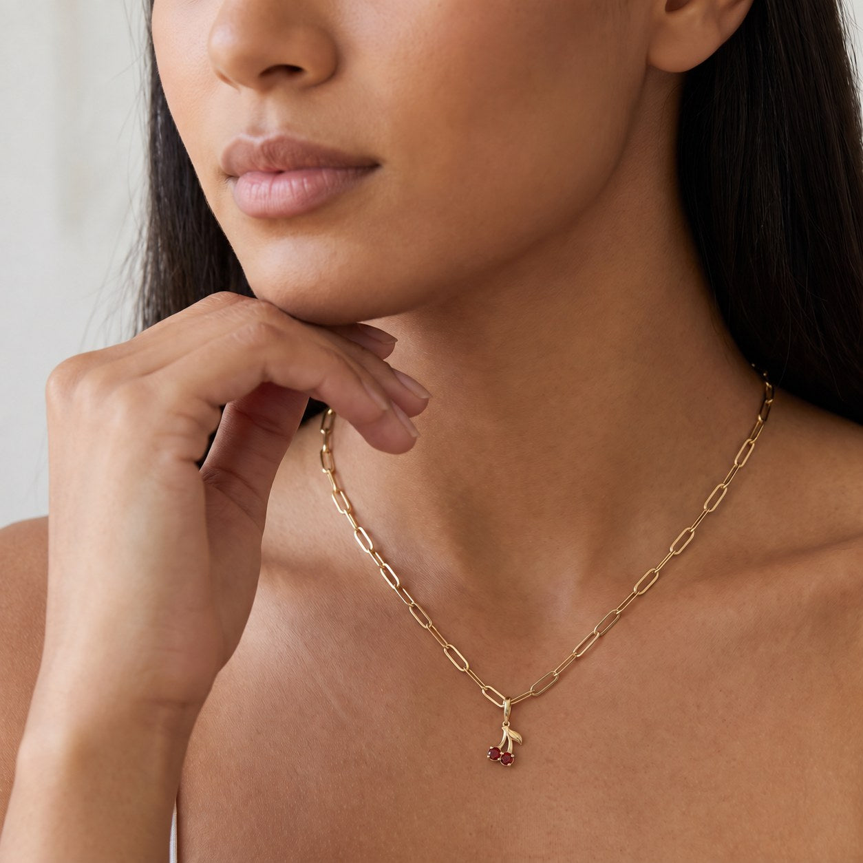 Natural Garnet Cherry Charm in 14K Yellow Gold, worn at the neckline on a paperclip chain shown for styling