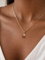 Natural Garnet Cherry Charm in 14K Yellow Gold, shown close on the neckline, two red garnets below a polished leaf; chain shown for styling