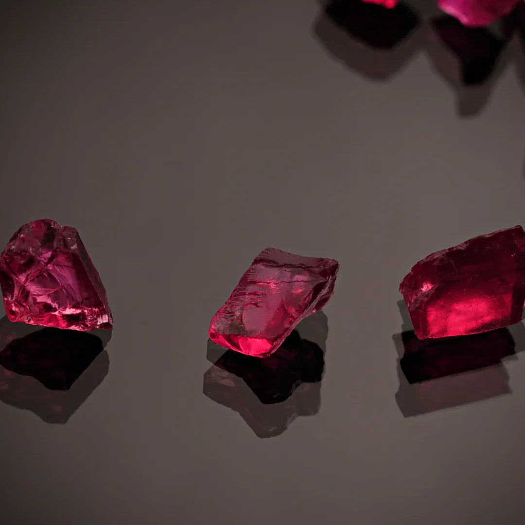 Rough uncut ruby crystals on a dark reflective surface