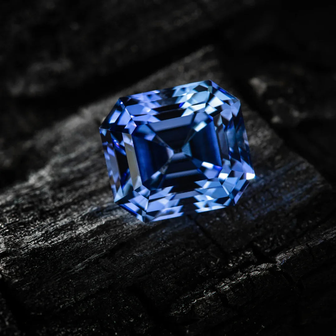 Asscher cut blue sapphire gemstone on dark textured surface