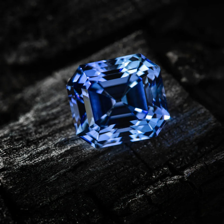 Asscher cut blue sapphire gemstone on dark textured surface
