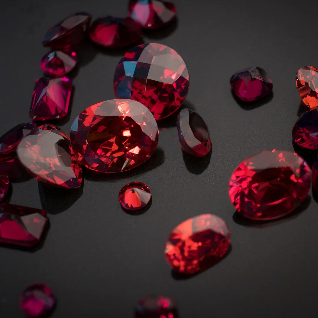 Assorted loose red rubies gemstones with various cuts on a black background