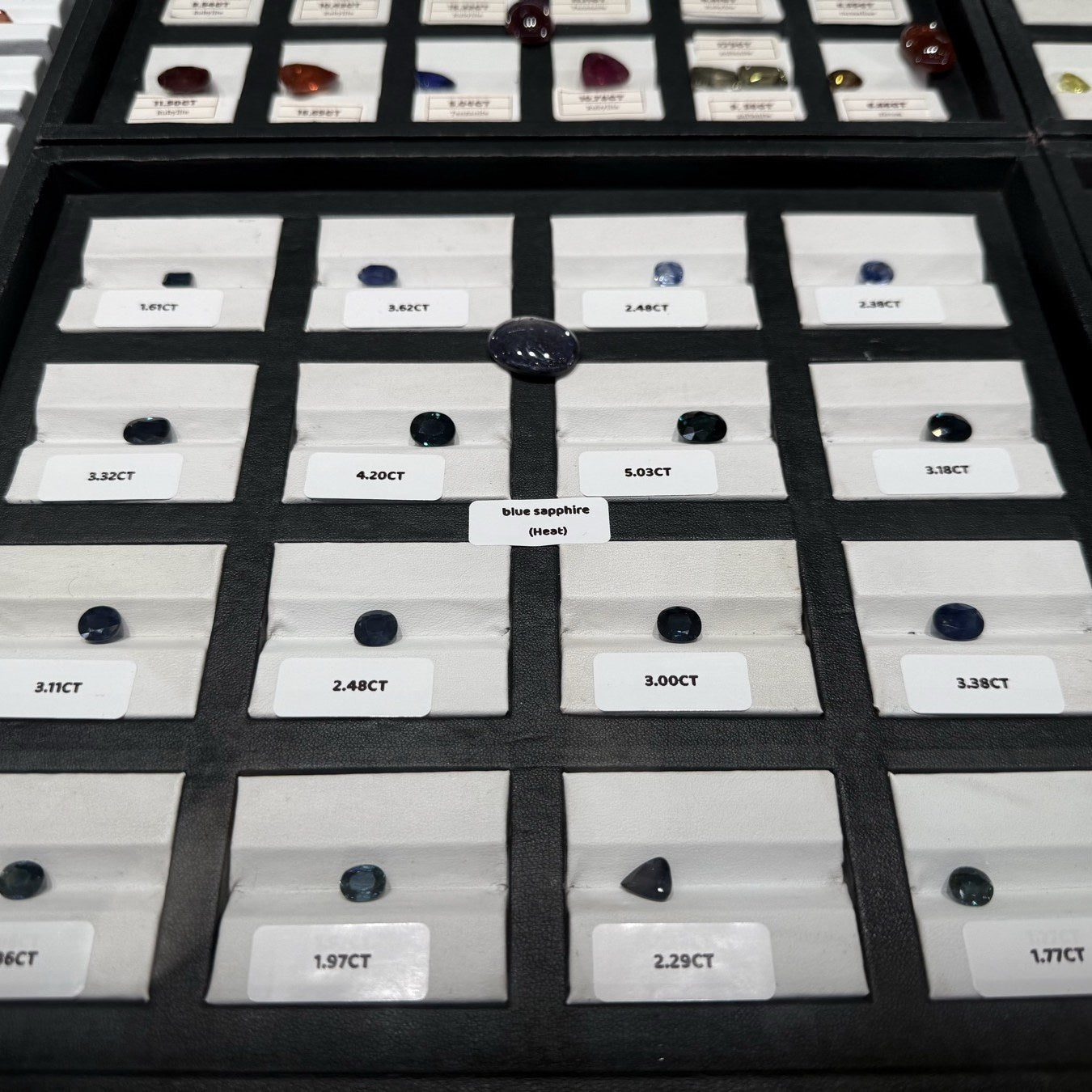 Collection tray of certified loose gemstones with carat labels