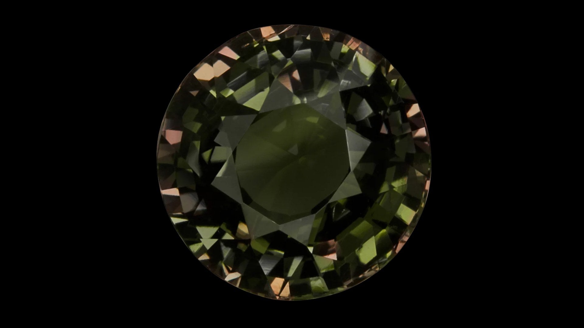 Round alexandrite gemstone with green-to-red color change on a black background