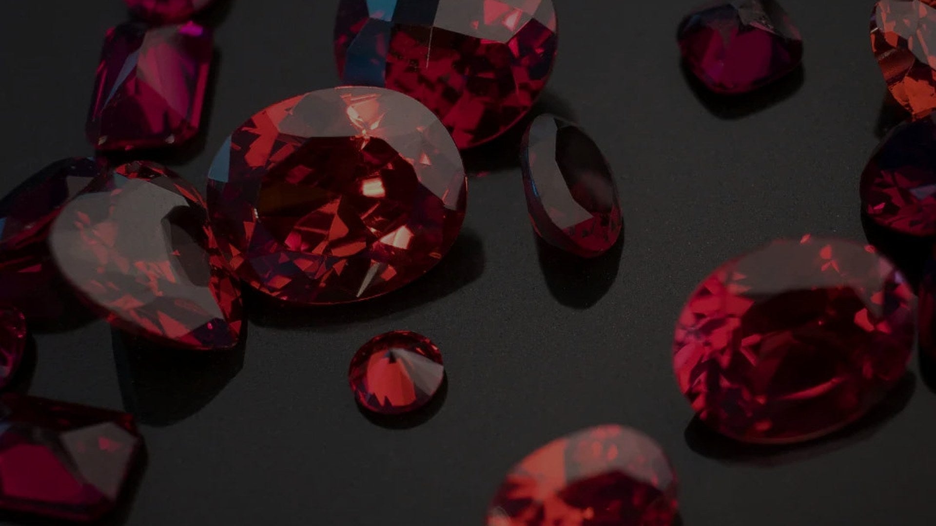 Scattered red garnet gemstones on a dark background