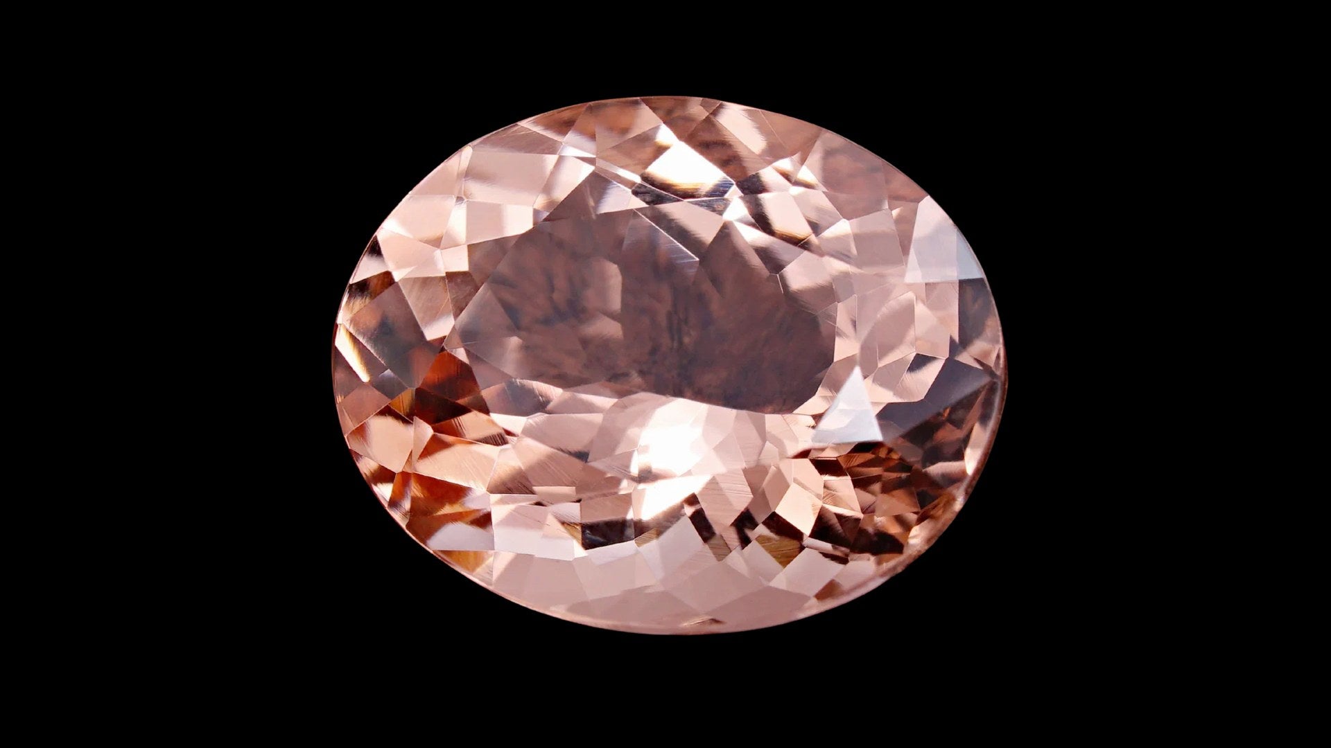 Oval blush-pink morganite gemstone on a black background