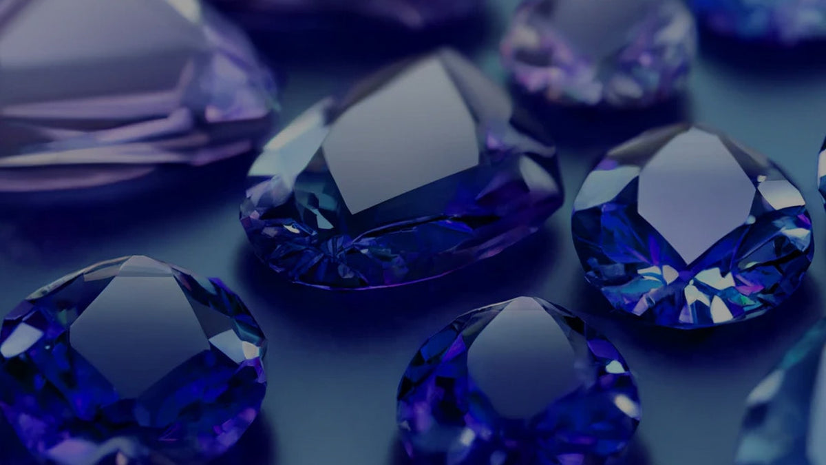 Assorted violet-blue tanzanite gemstones on a dark surface