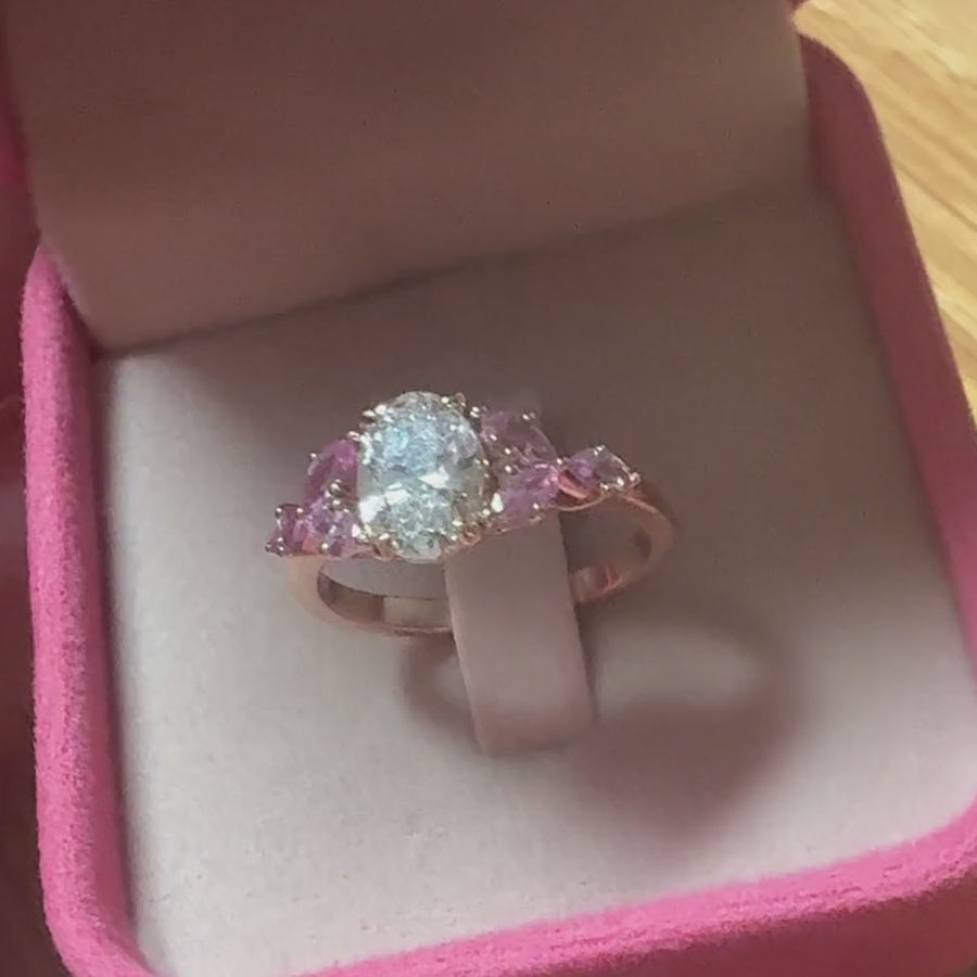 The finished oval diamond ring with pink sapphires in its box