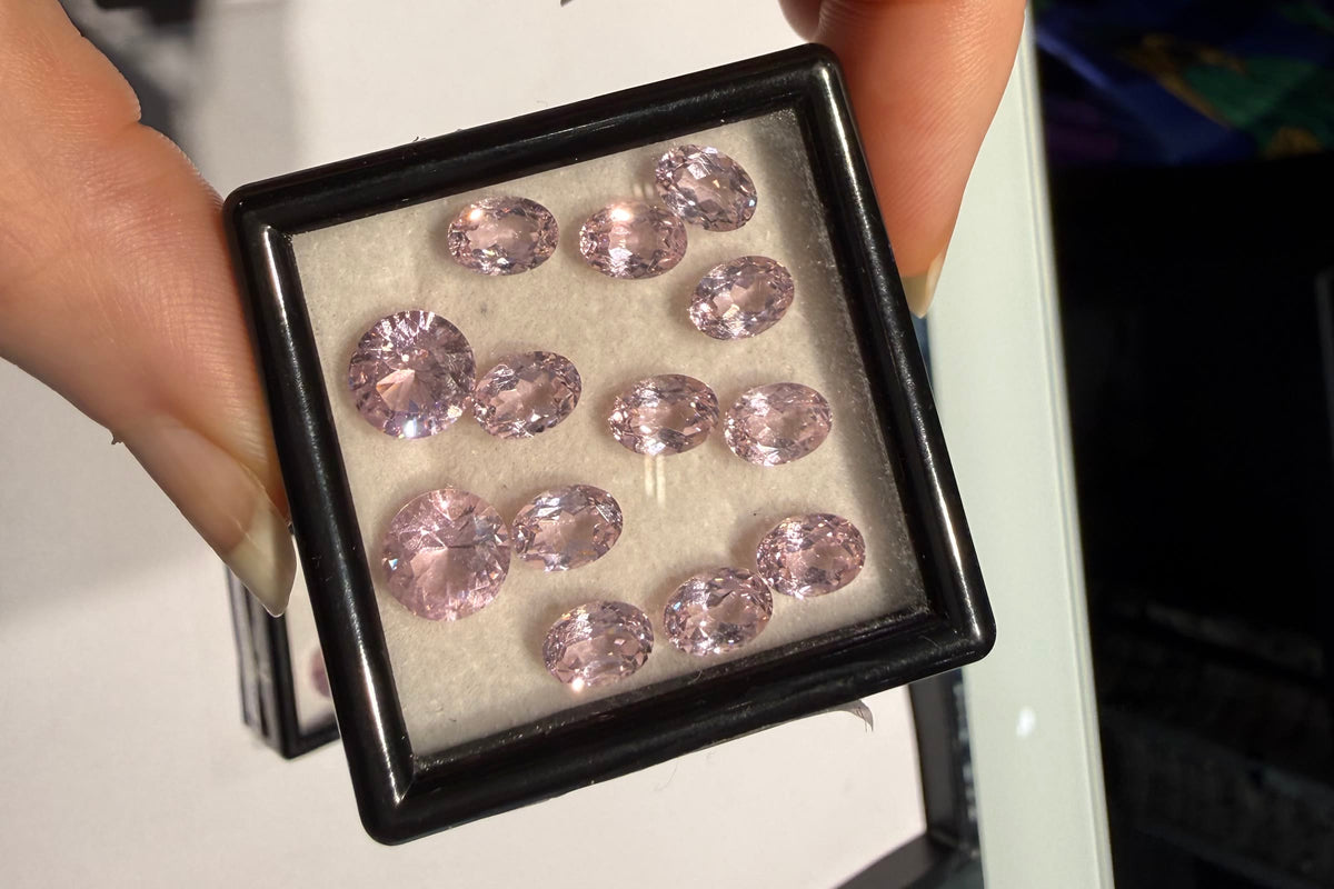 A box of pink gemstones selected for a client, held up to compare